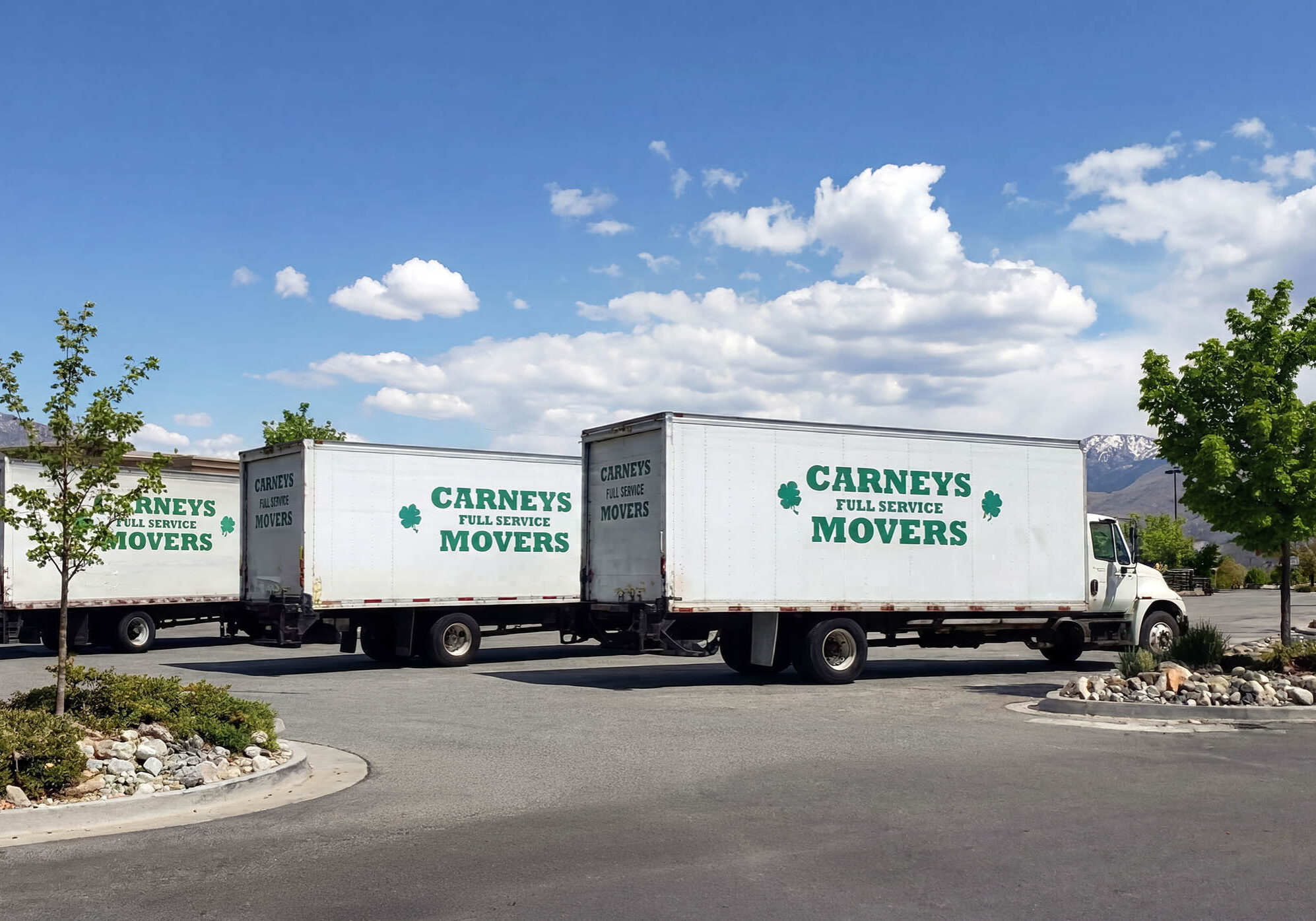 Three Carneys Full-Service Movers trucks parked with the Sierra Nevada mountains in the background near Reno and Sparks, Nevada